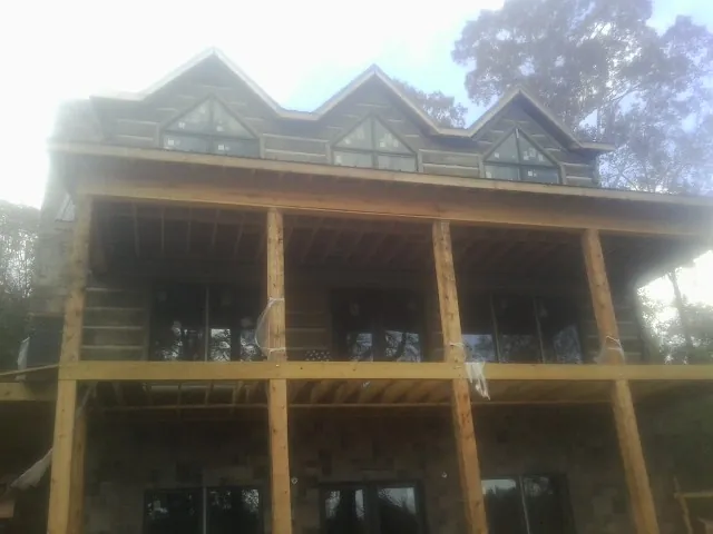 Dormers and porch framing on a large log home under construction — Roof Coating work by our crew in Fulton