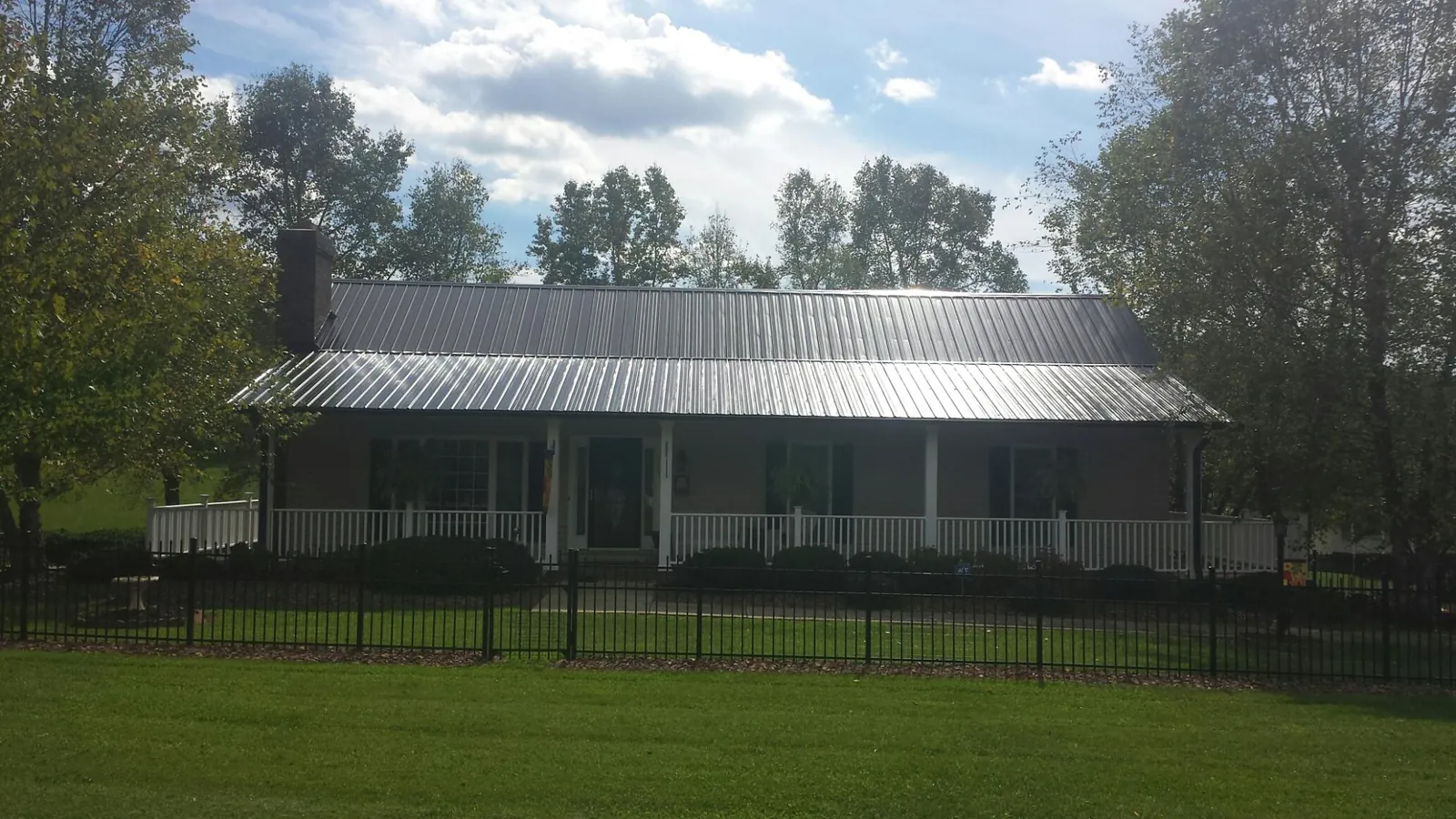 Gray metal roof on a brick ranch with a full width front porch in Fulton